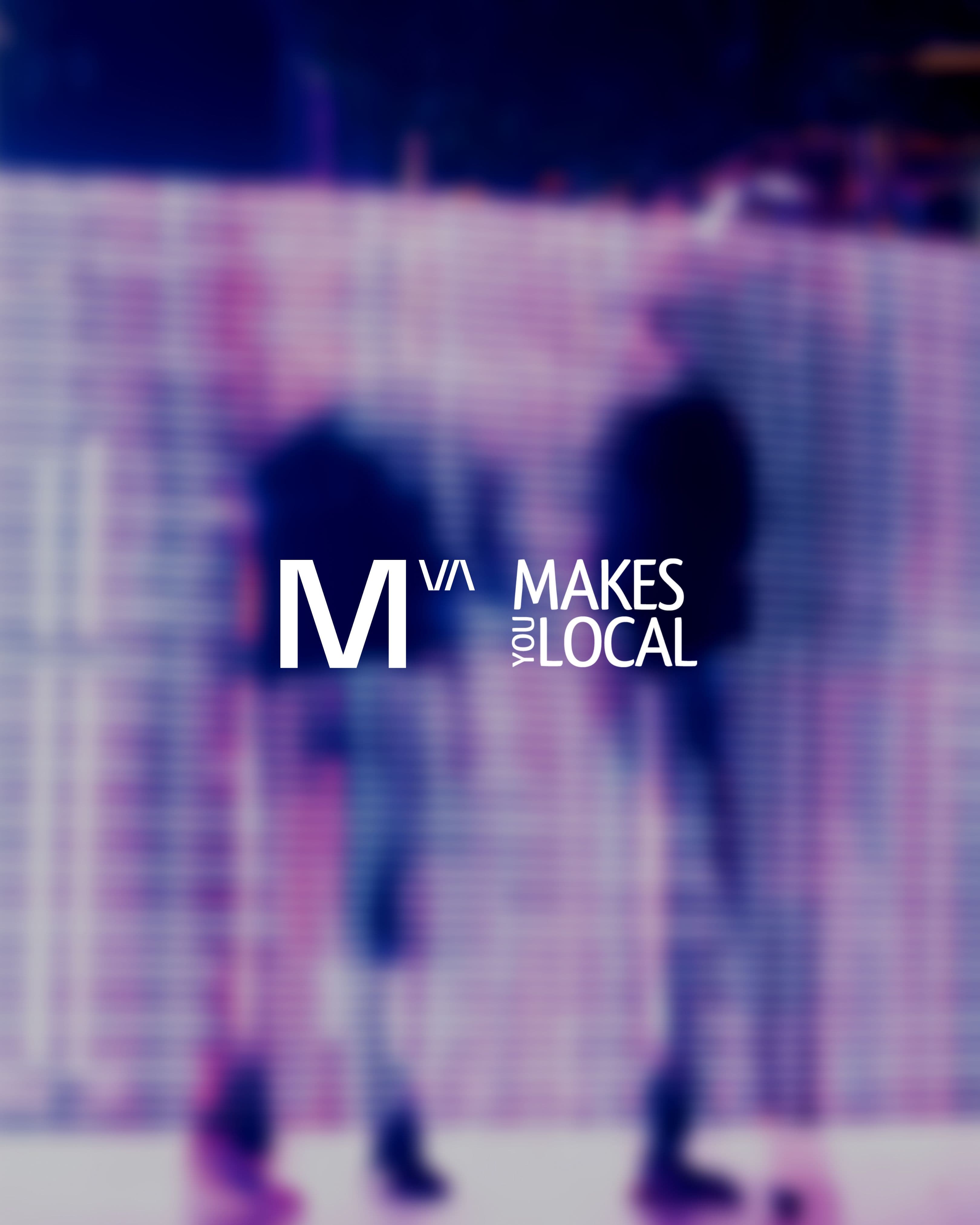 White text "M/VA MAKES YOU LOCAL" over a blurry purple and blue background with two indistinct figures.