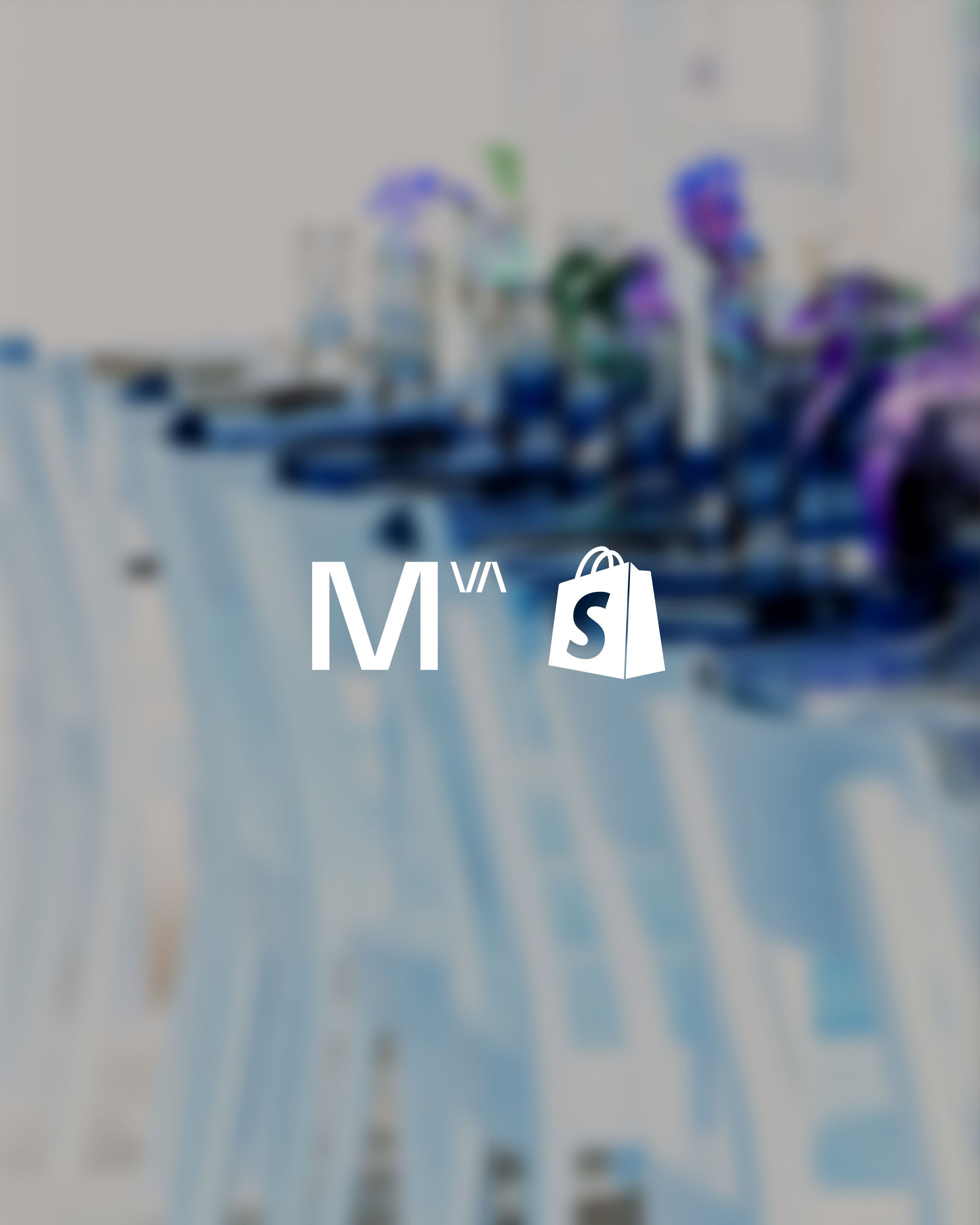 White M^VA text and shopping bag logo on a blurred background.